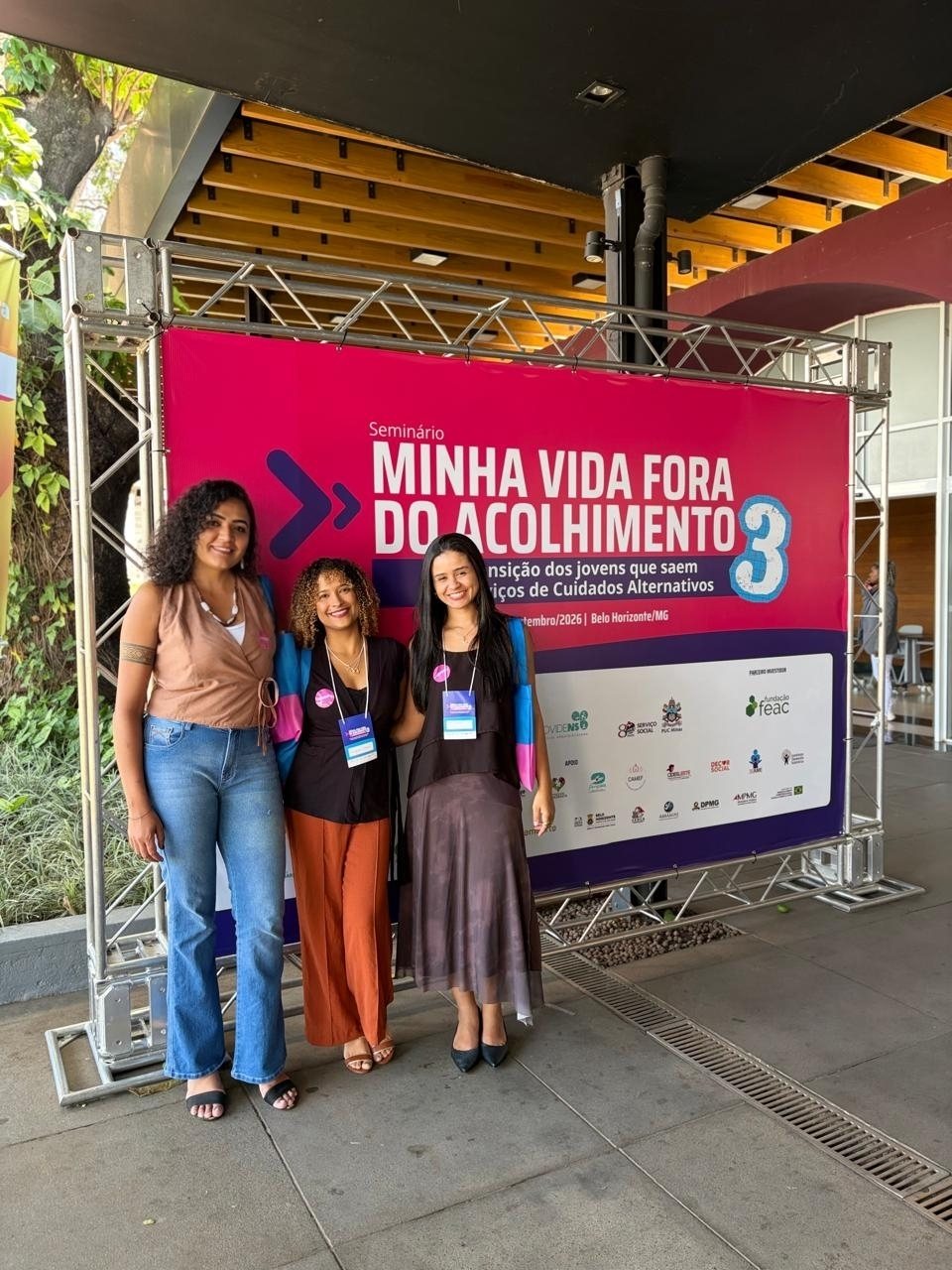 Representantes da Casa Aurora em frente ao banner do Seminário Minha Vida Fora do Acolhimento, em Belo Horizonte